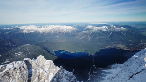 view on a lake from the summit of a snowy mountain in the alps