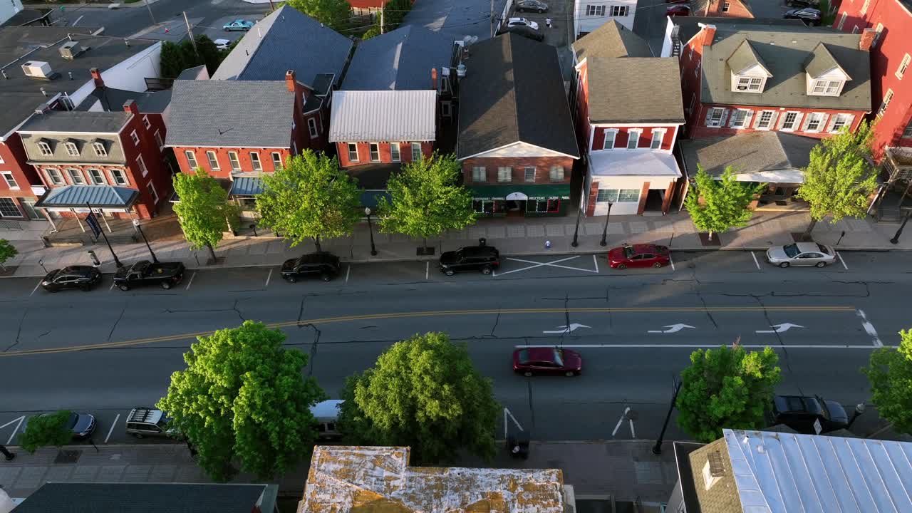 Shops and stores in historic american Buildings during sunrise. Aerial tilt down shot. Parking cars on street. Colored houses with porch in Ephrata, PA, USA.