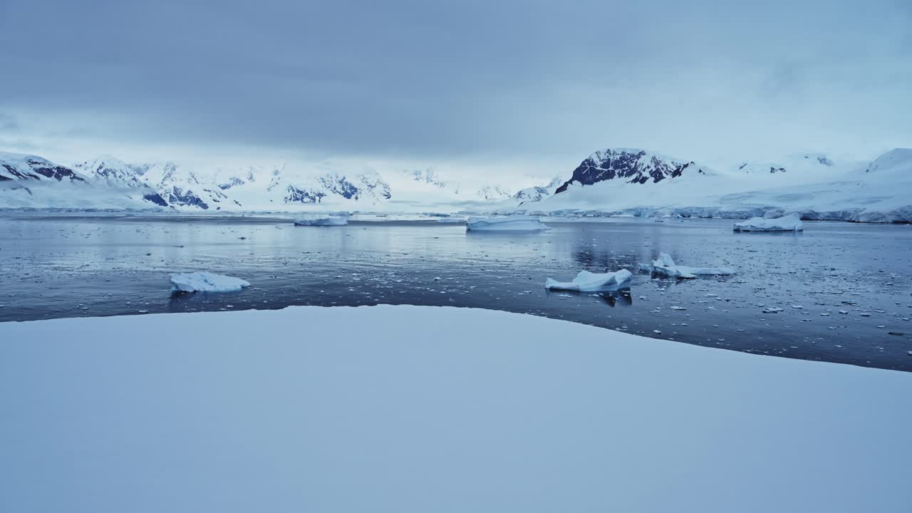 Winter Landscape with Snow Ocean and Mountains in Antarctica, Icebergs in Sea in Beautiful Dramatic Dark Moody Blue Coastal Seascape on Antarctic Peninsula Coast, Icy Winter Sea Scene with Ice