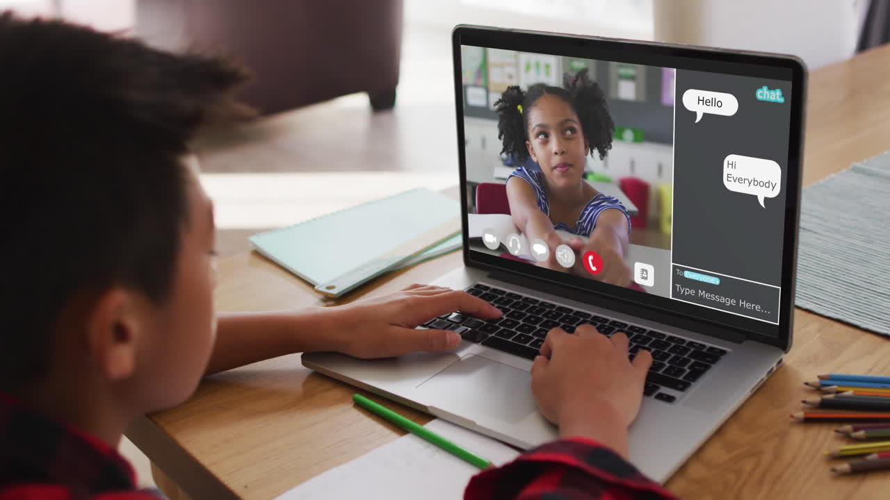 Schoolboy using laptop for online lesson at home, with his colleague and web chat on screen