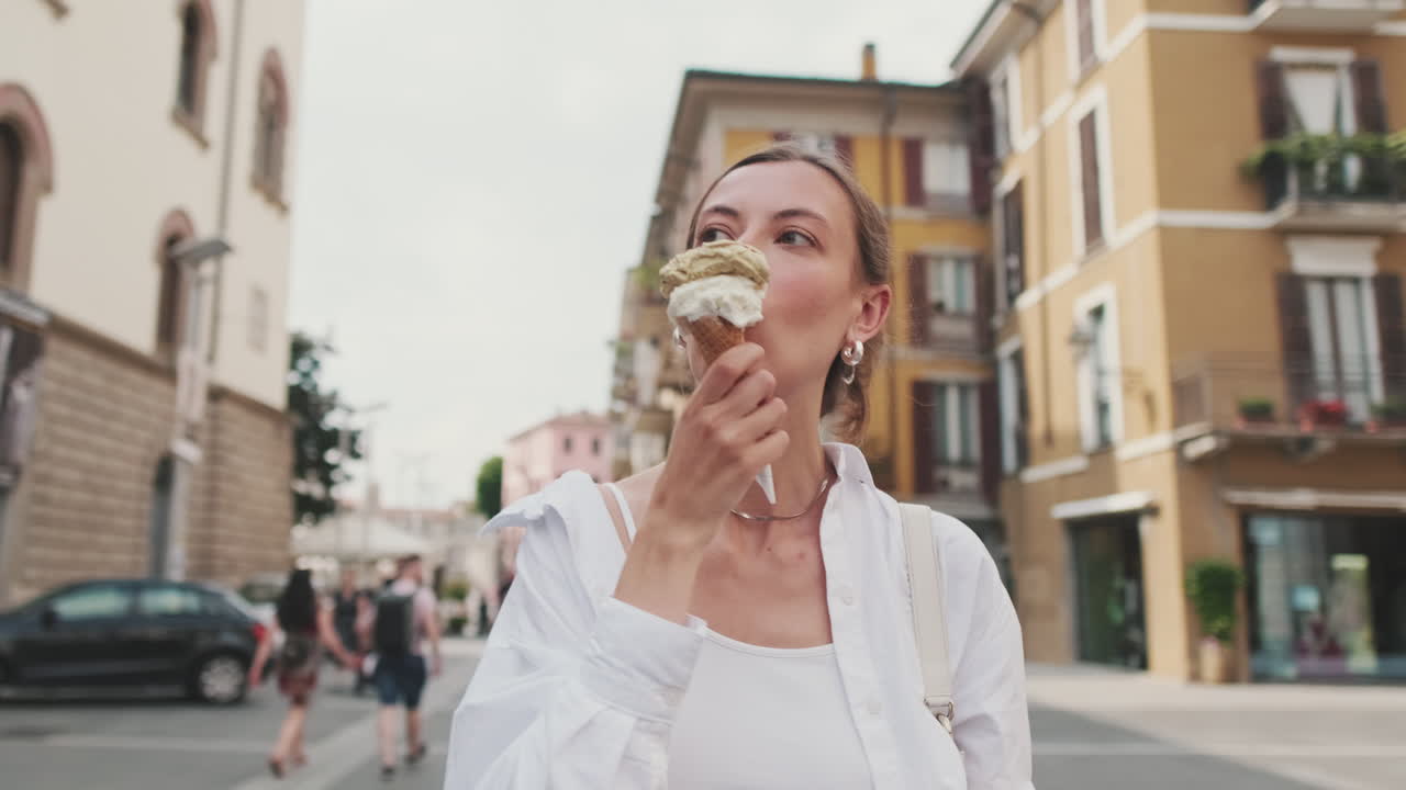Młoda kobieta jedząca lody podczas spaceru po ulicy miasta