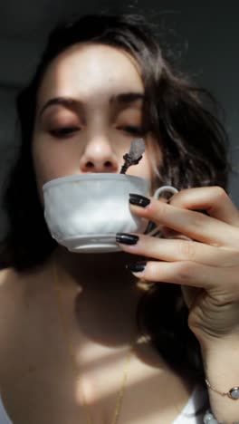 woman drinking tea with crystal tea spoon