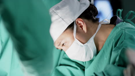 아시아 여성 외과 의사 가 병원 의 수술실 에서 환자 를 수술 하고 있다.