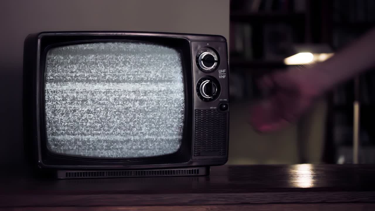 Mano maschile che colpisce un vecchio televisore finché non appare lo schermo verde. Risoluzione 4K.
