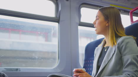 two businesswomen commuting to work on train talking together in carriage