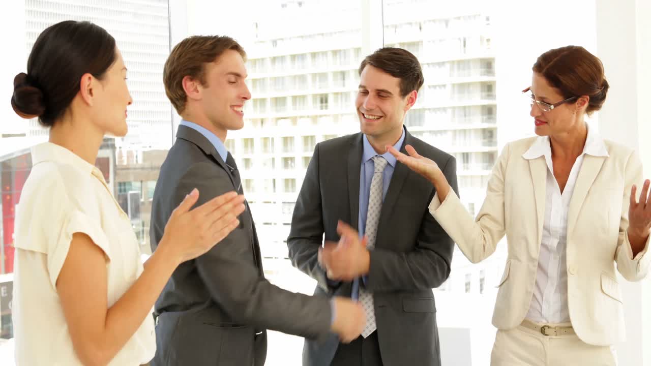 gente de negocios estrechando la mano en la entrevista mientras otros aplauden