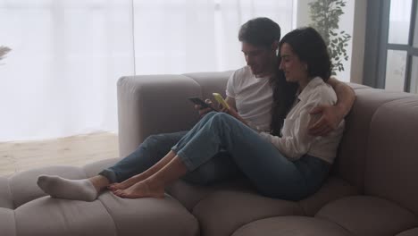 pareja feliz viendo teléfonos móviles juntos. personas relajadas buscando móviles