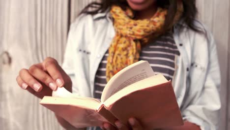hipster leyendo un libro contra una valla de madera