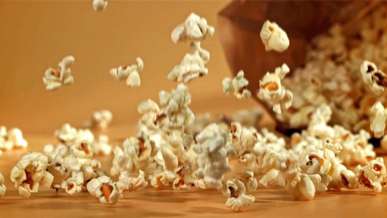 Popcorn in caduta e dispersione al rallentatore su uno sfondo beige