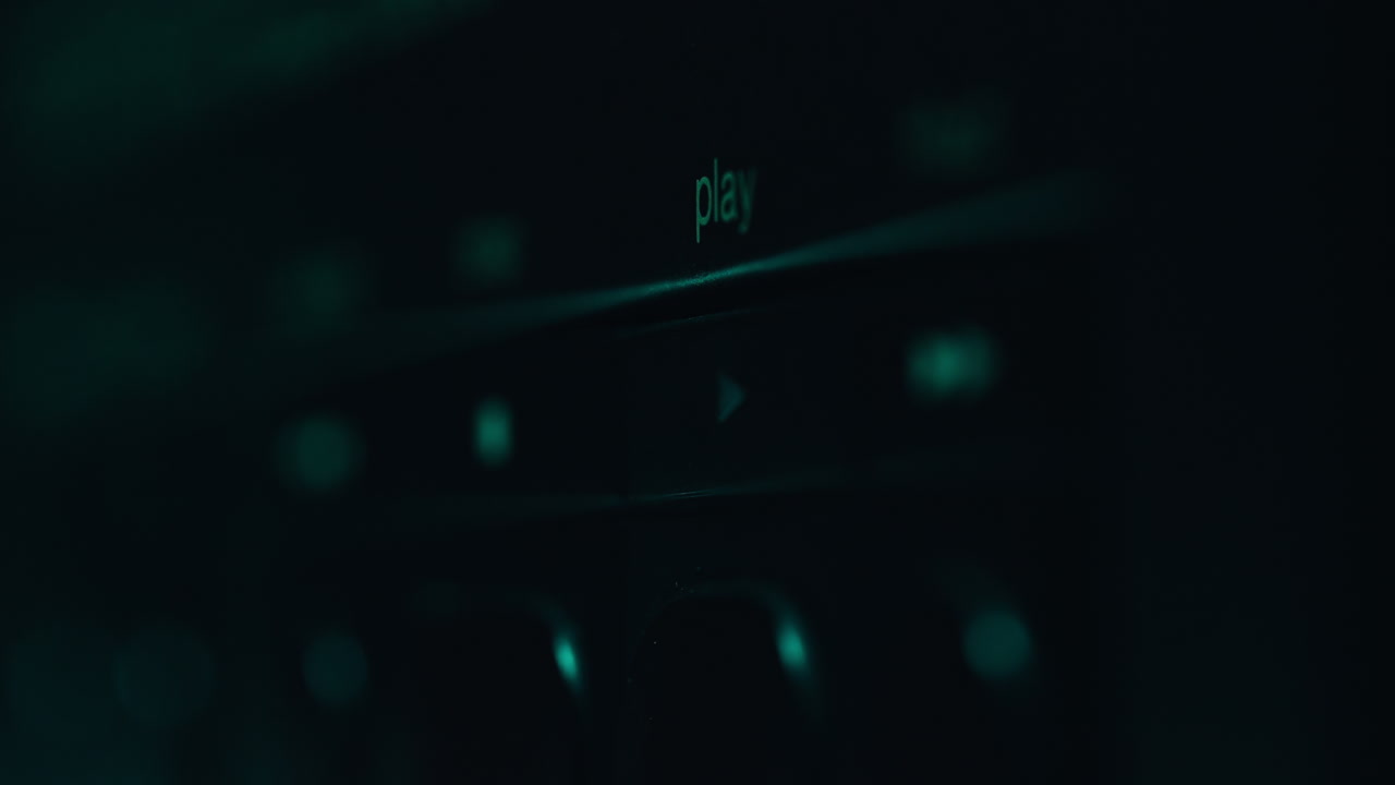 Finger press play knob at black panel audio device closeup. Music listener
