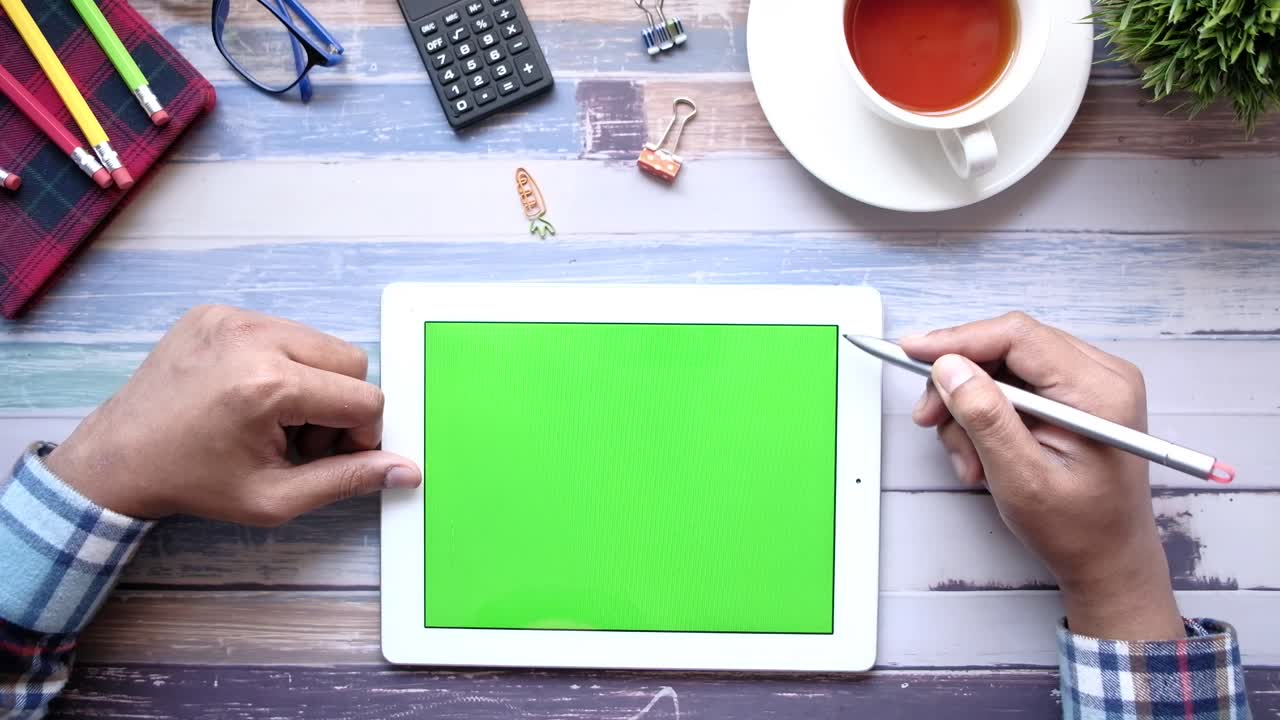 Person using tablet with green screen