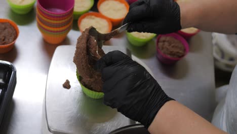 pastry chef scoops delicious chocolate batter into cupcake paper