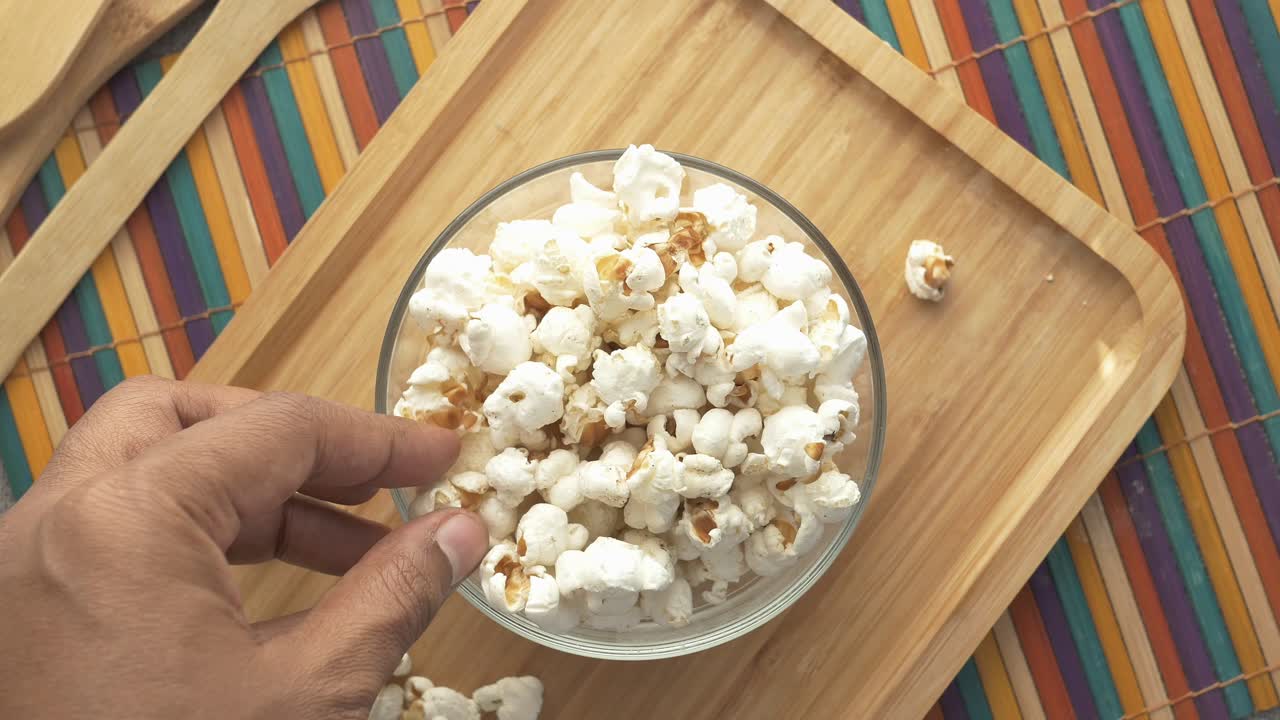 la mano alcanzando las palomitas de maíz
