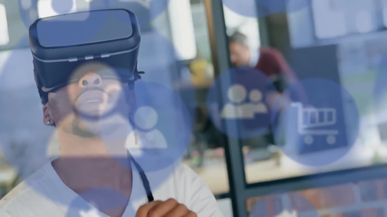 Flere digitale ikoner svævende mod en afroamerikansk forretningsmand iført VR-headset på kontoret.