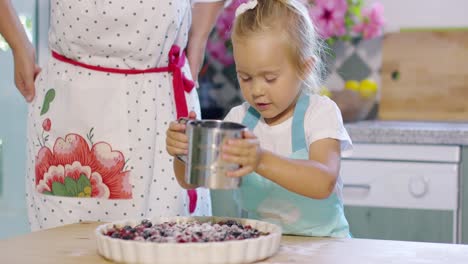 una niña sonriente salpicando azúcar en una tarta