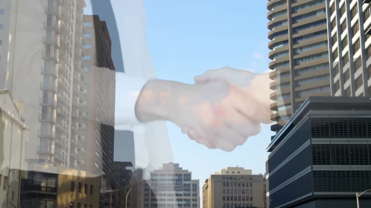 Sección media de un empresario y una empresaria dándose la mano con edificios altos de fondo