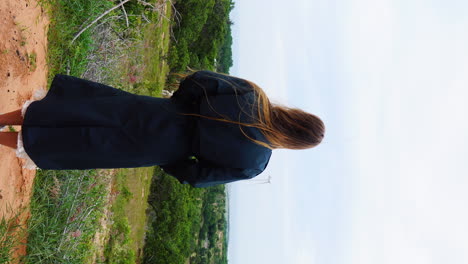 a girl dressed in blue looking over to the windmill farm and absorbing the scenic view