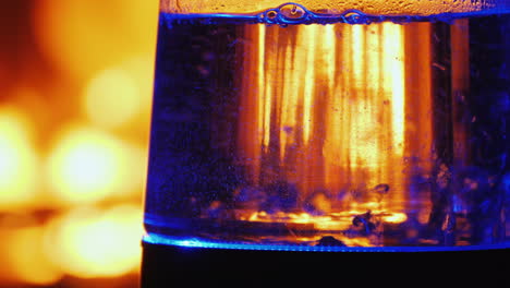 water boils in a backlit electric kettle a fire in the background burns in the background