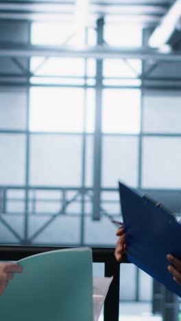 vertical video data center engineer greeting colleague, examining system diagnostics paperwork