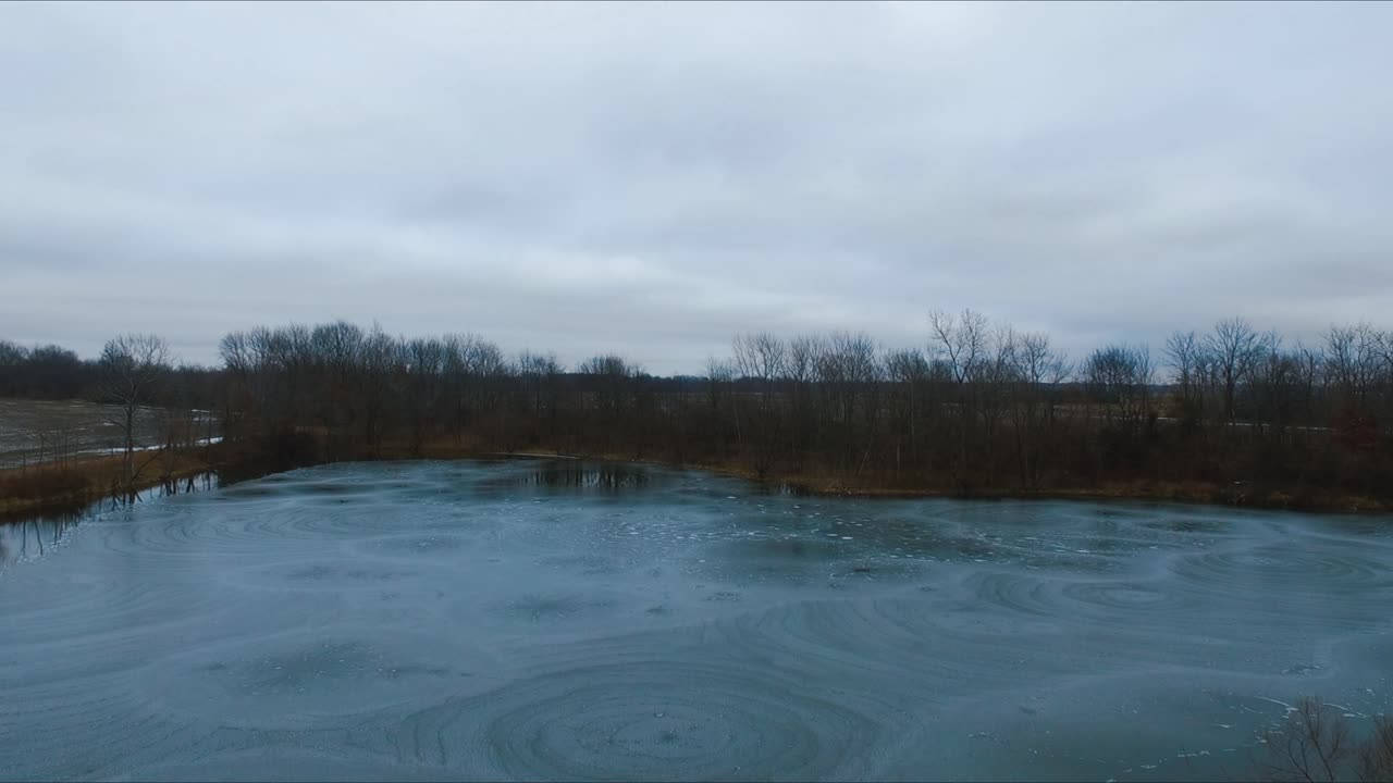 Drone flying over a partially frozen lake that has very unique ice formations on it