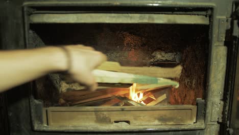 adding kindling sticks to wood burning stove fire