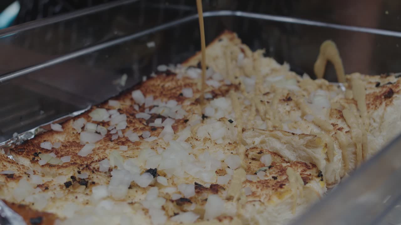 요리 트레이에 있는 슬라이더 버거 빵에 머스타드 소스를 추가하는 모습