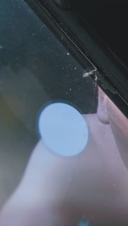 person touches broken mobile phone screen with splits on black background extreme close view