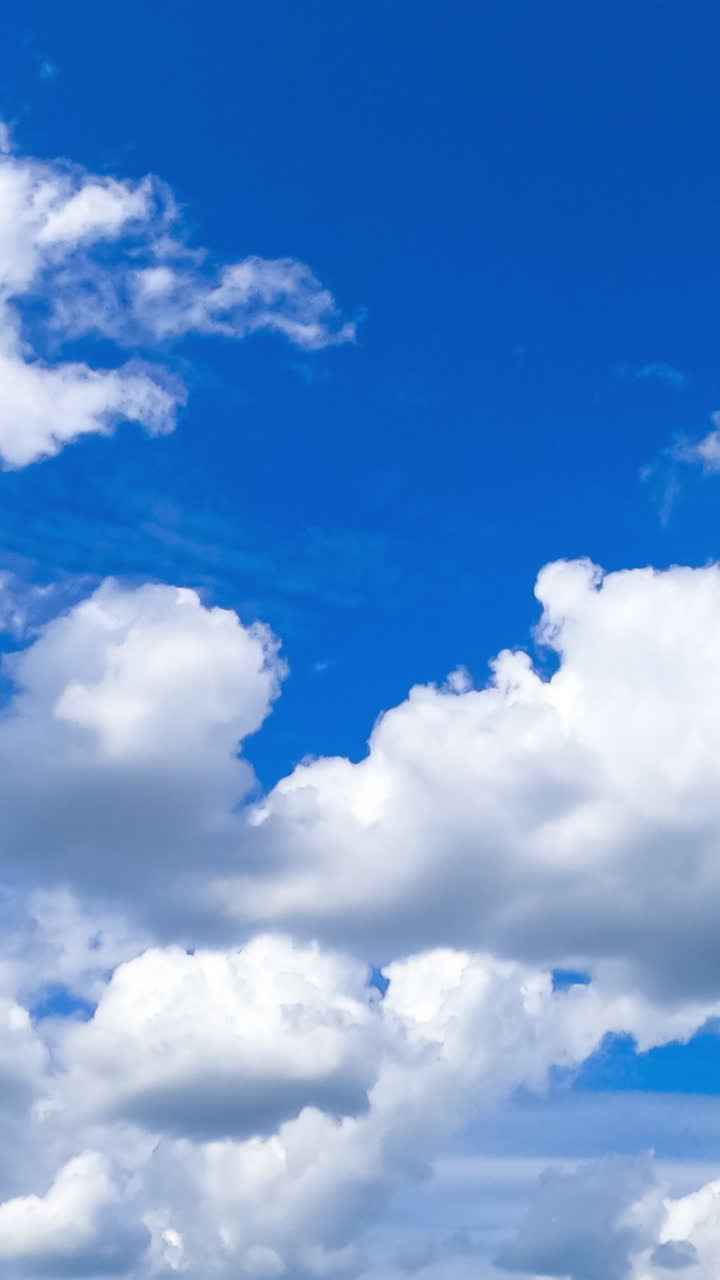 Heavenly beautiful cumulus clouds transforming in the blue skies. Light spindrift clouds at backdrop. Timelapse. Vertical video