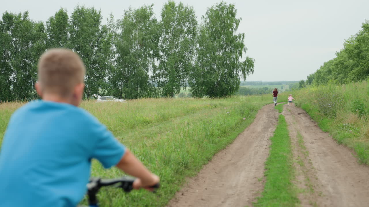 Youth pedaling outdoors, Child enjoys sunny cycling adventure, Boy rides his bicycle freely across bright countryside, Fairskinned young boy pedals happily along expansive sunlit open trail