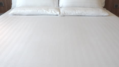 white sheets and pillows on king size bed in comfortable suite bedroom, tilt up