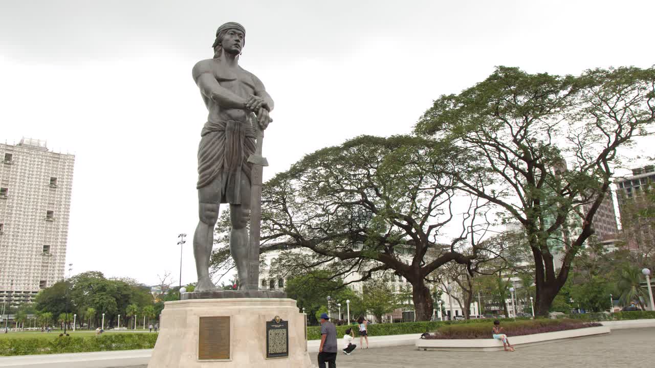 Ampia inquadratura statica del monumento in bronzo di Lapu-Lapu sotto un cielo coperto a Manila