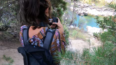 female young caucasian photographer taking photo front to river in patagonia argentina