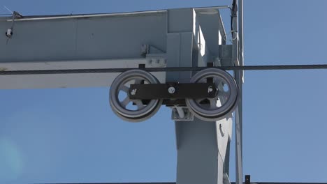 cable car passing over wheels atop of a tower, blue sky background, close up