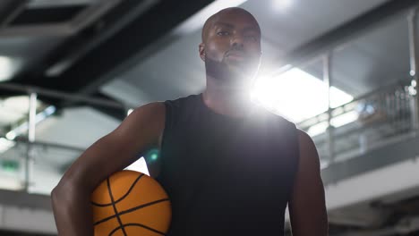 portrait shot of male basketball player on court holding ball under arm 1