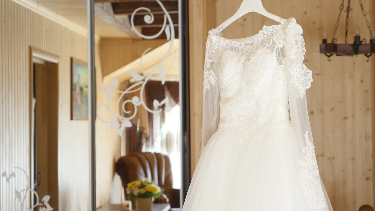 Fluffy wedding dress on a hanger in hotel room. Wedding morning