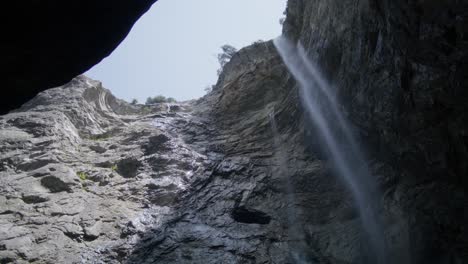 large waterfall in cave opening | grindelwald switzerland cave in glacier canyon, europe, 4k