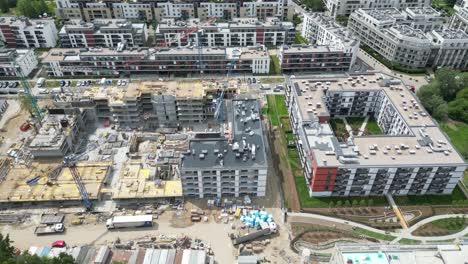 Aerial-top-down-view-on-the-rooftop-of-an-apartment-building-under-construction-with-tower-crane-and-a-lot-of-workers-laying-metal-rebar