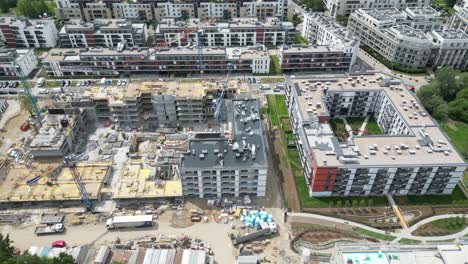 vista aérea de arriba hacia abajo en el techo de un edificio de apartamentos en construcción con una grúa de torre y muchos trabajadores colocando barras de metal