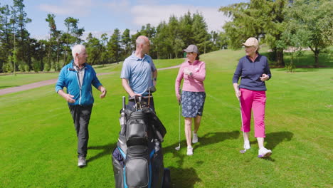 golf players walking with clubs and talking on golf course