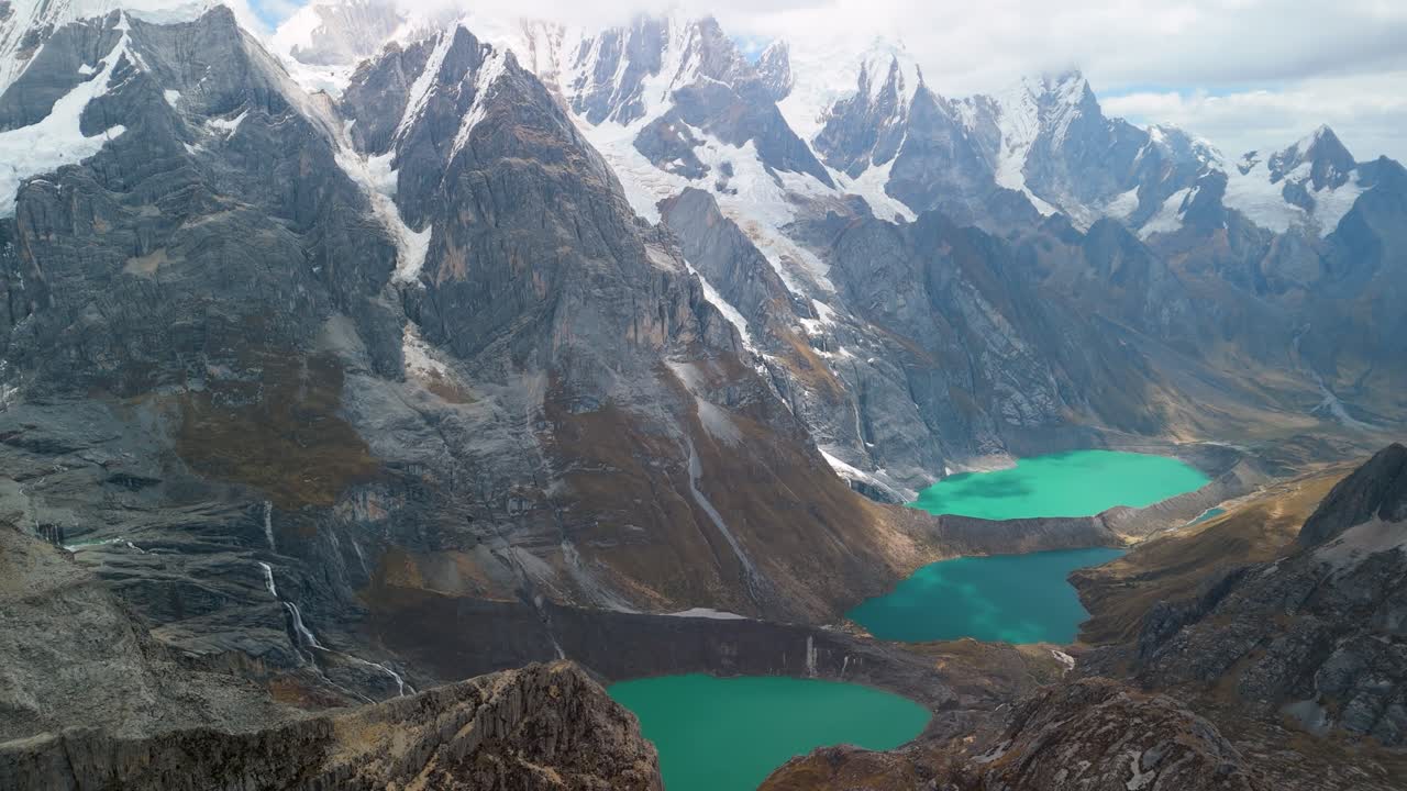 Spectacular aerial panorama reveals the iconic Tres Lagunas - Jurau, Solteracocha, and Azulcocha - amidst the majestic Cordillera Huayhuash peaks in Peru