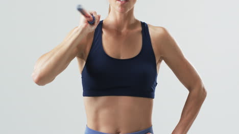 Young-Caucasian-athlete-woman-in-fitness-attire-holds-a-javelin-on-a-white-background,-with-copy-spa