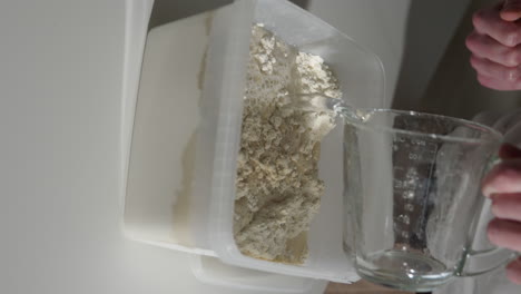 pouring water into a plastic container with flour and yeast preparing dough for homemade bread