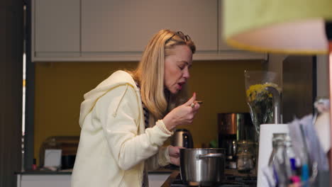 woman cooking and tasting food in the kitchen