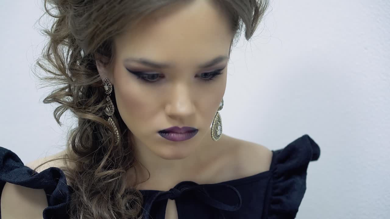 Young girl in the office sitting at the laptop typing text sometimes looking at the phone Portrait