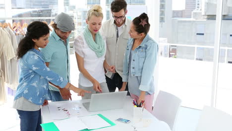 Fashion-team-brainstorming-together-using-laptop-giving-thumbs-up-to-camera