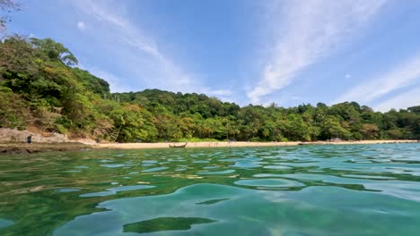 tranquil ocean scene with lush greenery and clear skies at laem singh beach, phuket. captured in vibrant daylight, showcasing natural beauty