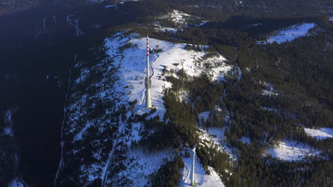 Tiro-De-Seguimiento-Aéreo-Lento-De-Una-Turbina-Eólica-Y-Una-Torre-De-Transmisión-En-Una-Meseta-Cubierta-De-Nieve