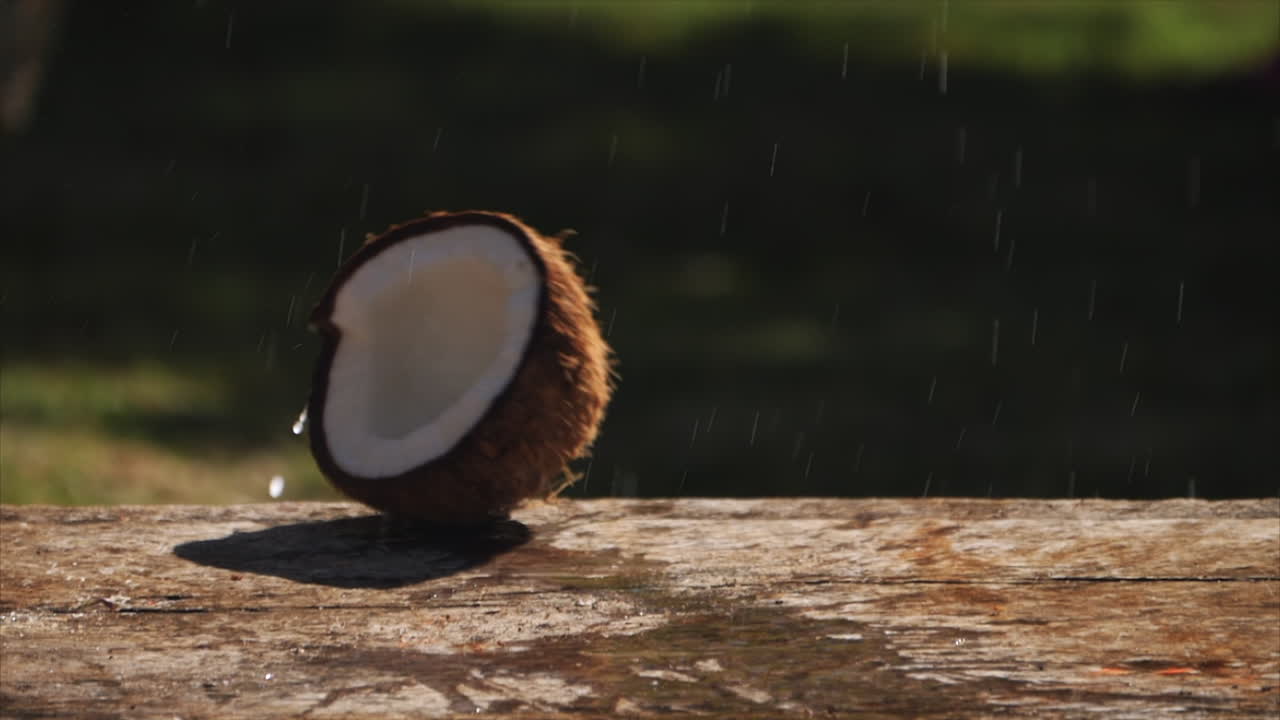 un coco golpea un banco de madera y revienta leche salpicada en cámara lenta