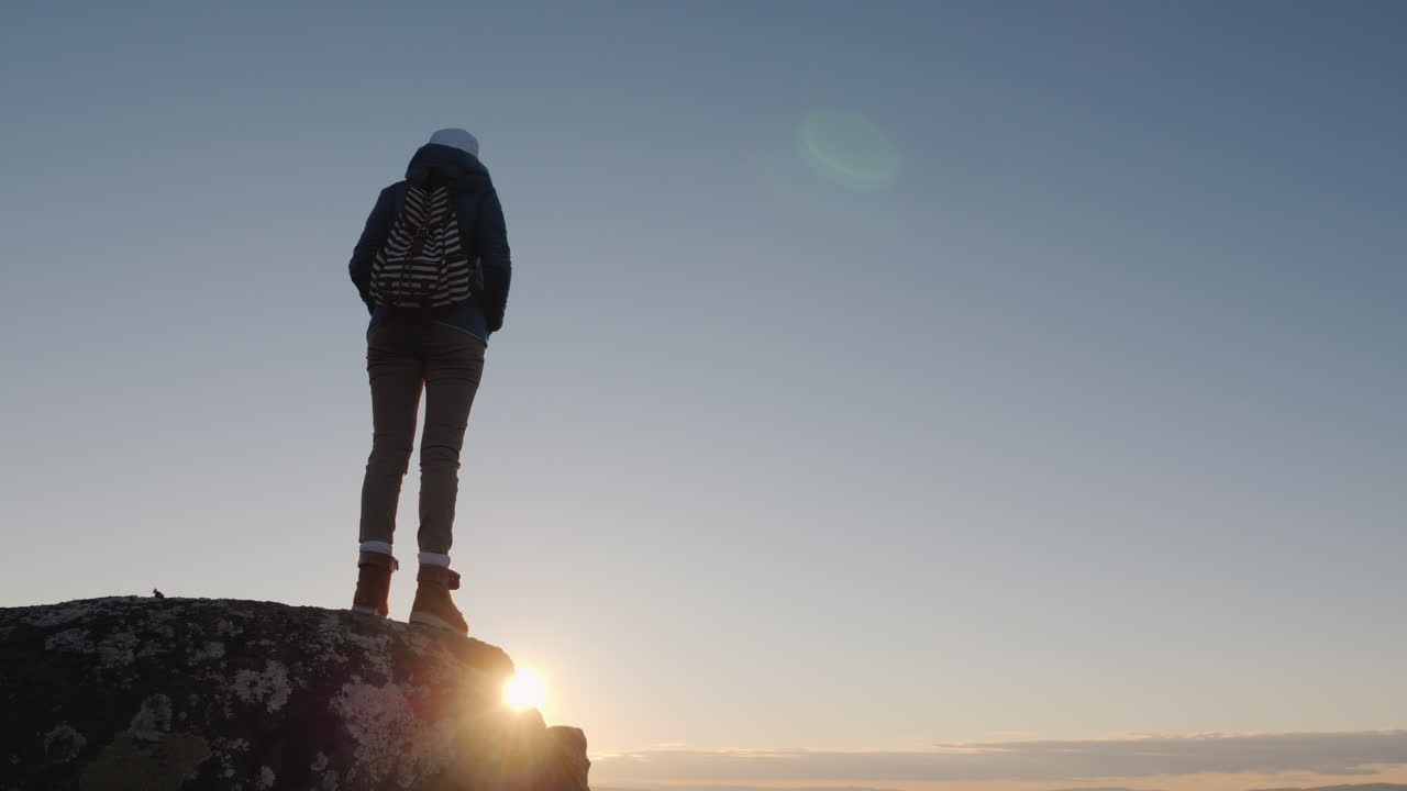 una mujer viajera exitosa en la cima de la montaña levanta las manos para llegar a la cima del conc