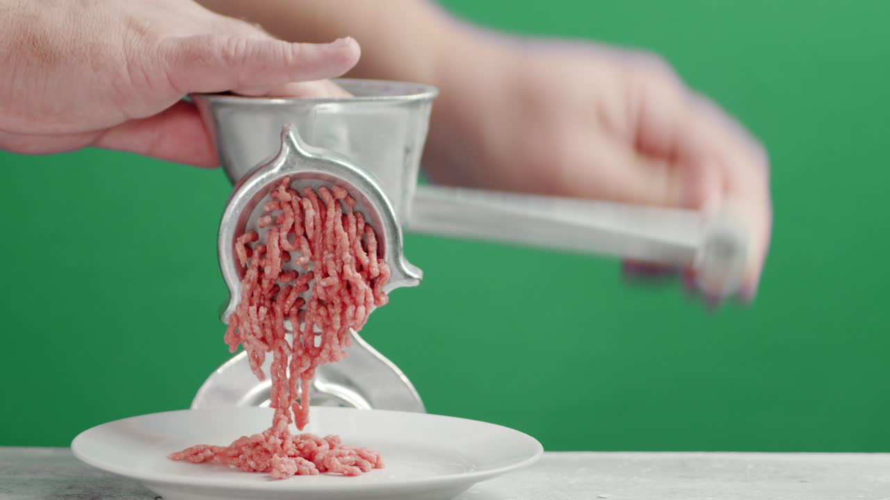남자의 손은 고기 밀기에서 생 고기를 만니다.